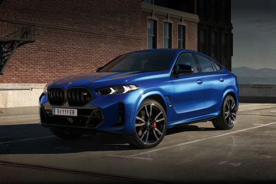 Blauer BMW X6 steht auf einem Parkplatz vor einer roten Ziegelwand